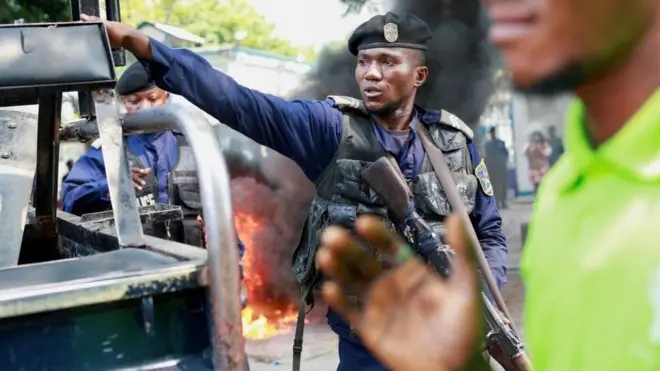 Umupolisi akora ikimenyetso mu gihe cy’imyigaragambyo hafi y’ibiro bikuru by’ubutumwa bwa MONUSCO, rwagati muri Kinshasa, muri Repubulika ya Demokarasi ya Congo, ku itariki ya 12 Gashyantare (2) mu 2024 