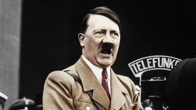 Adolf Hitler açık kahverengi askeri üniformasıyla Telefunken marka mikrofon önünde konuşma yapıyor