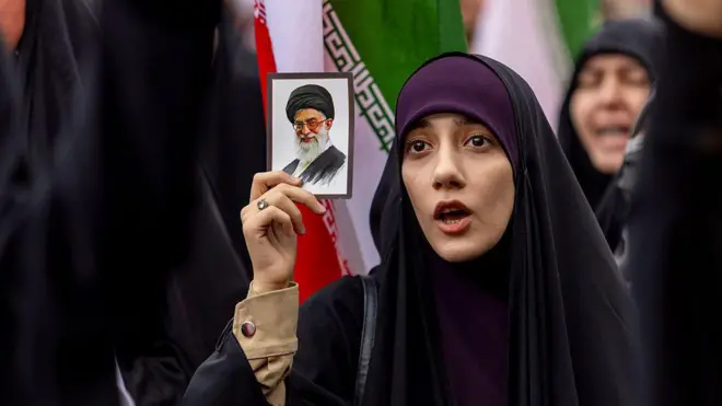 အီရန်ကို အမေရိကန်နဲ့အစ္စရေးတို့တိုက်ခိုက်မှုကို ဖေဖော်ဝါရီလ ၂၈ ရက်မှာ တီဟီရန်မြို့မှာ ပြုလုပ်တဲ့ဆန္ဒပြပွဲအတွင်း ခါမေနီရဲ့ဓာတ်ပုံကိုင်ထားတဲ့ အီရန်အမျိုးသမီးတစ်ဦး 