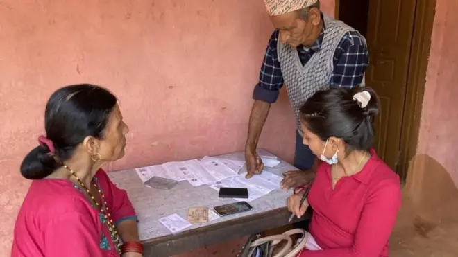 बाग्लुङमा स्वास्थ्य बीमा फारम भर्दै एक वृद्ध