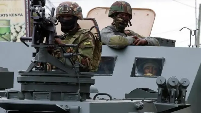  Umusirikare w’Ingabo za Kenya (Kenya Defense Forces) afashe ikigwanisho ari ku modoka ya gisirikare mu gihe ingabo ziriko zirakizura amabarabara mu nyiyerekano yo kwiyamiriza igikorwa c’igiporisi mnu kwica abantu bari mu myiyerekano banka amakori yari mw’itegeko rigenga amafaranga reta izokoresha mu 2024-205