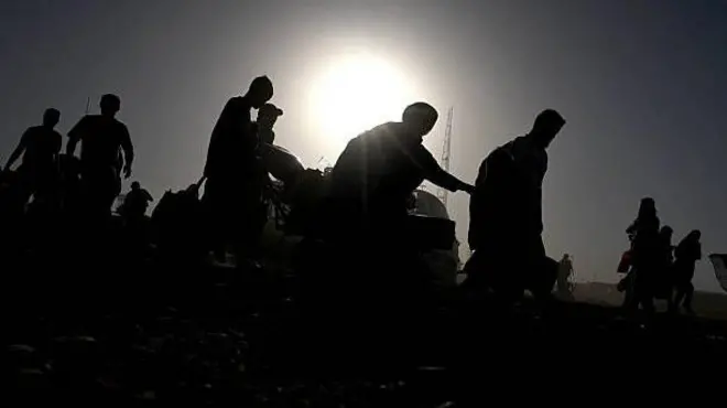 تصویر شماری از مهاجرانی که ازپاکستان به افغانستان اخراج شده اند. تصویر تاریک است چهره‌های شان معلوم نمی‌شود اما مهاجران در یک قطار همه به سمت راست تصویر درحرکت هستند. 