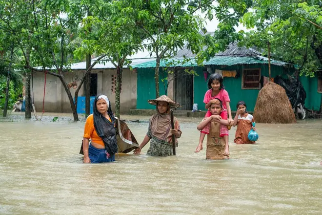 চট্টগ্রামের বন্যা আক্রান্ত একটি এলাকায় কিছু মানুষ পানির মধ্যে দাঁড়িয়ে রয়েছেন