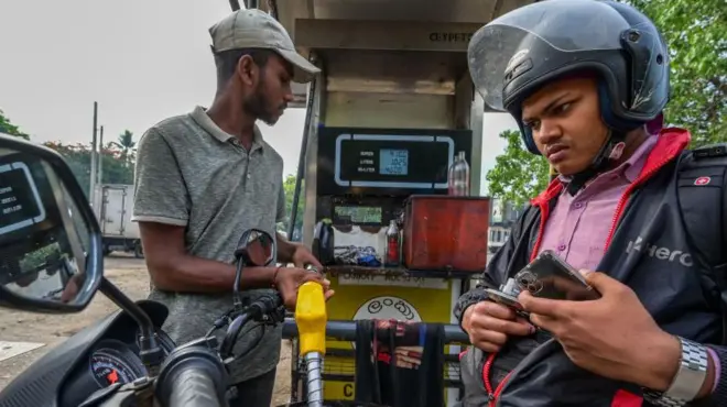 A worker fills petrol in an motorbike at a fuel station 