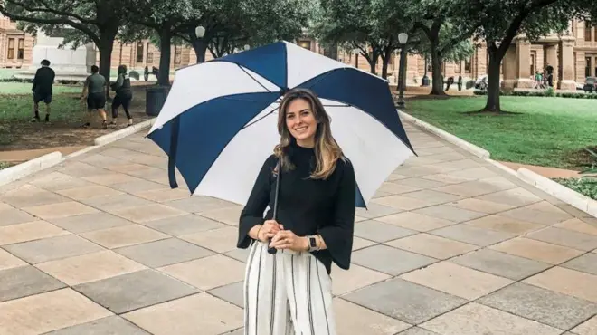 Eve Wiley segurando um guarda-chuva e sorrindo