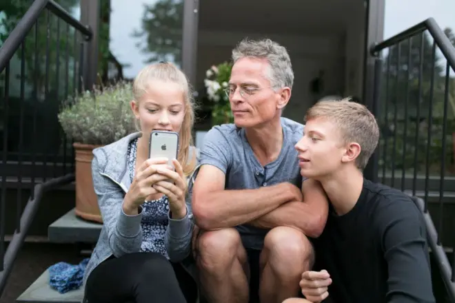 Filhos e pai olhando celular