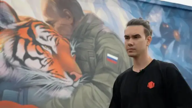 Filipp Dulmachenko, junto al mural que ha pintado con la imagen de Putin abrazado a un tigre siberiano.