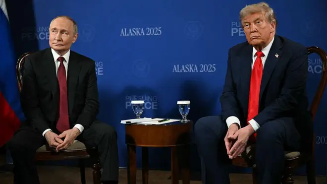 Трамп і Путін сидять поруч один з одним під час саміту щодо України у серпні, позаду них на синій стіні написи Аляска-2025