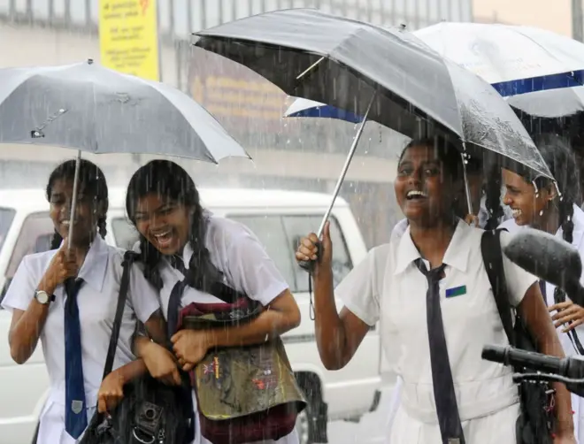 2008 සැප්තැම්බර් 5 වන දින කොළඹ ඇද හැලෙන වර්ෂාව මැදින් ගමන් කරන ශ්රී ලාංකික පාසල් සිසුවියන් සිනහ වෙමින්.