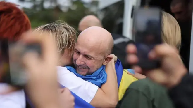 A Ukrainian man held in Russia for three and a half years grins and hugs a woman on his release in August 2025