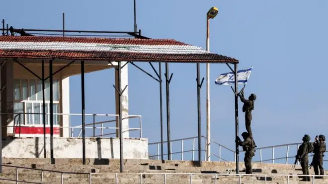 جنود إسرائيليون يحاولون رفع العلم الإسرائيلي في سوريا، بعد الإطاحة بالرئيس السوري بشار الأسد، كما شوهد من مجدل شمس في مرتفعات الجولان المحتلة من قبل إسرائيل، 23 ديسمبر 2024. الصورة التقطت نهاراً.