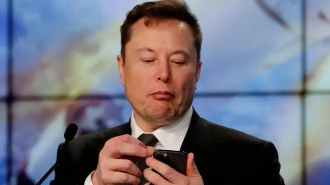 E﻿lon Musk le propriétaire de Twitter en train de manipuler un téléphone.