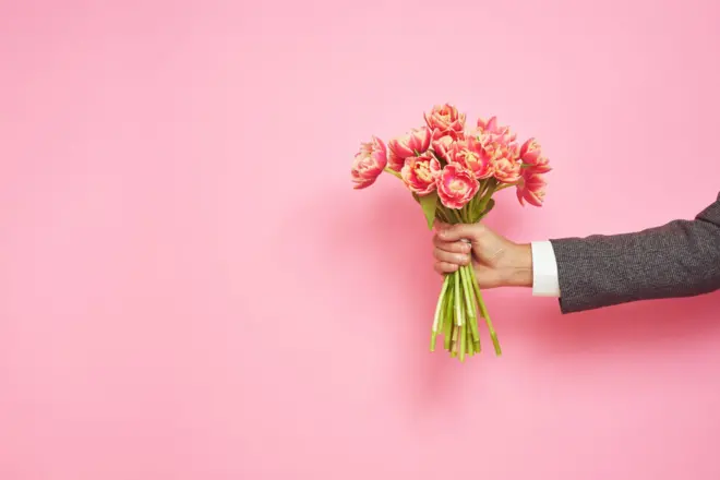 Mão de homem segurando buquê de flores
