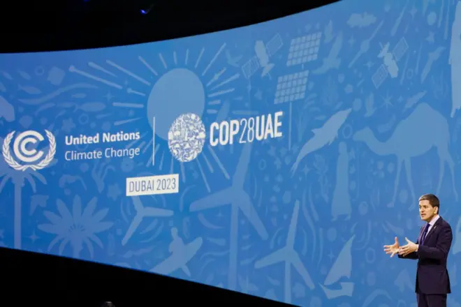 Man stand in front of COP28 UAE Dubai 2023 banner