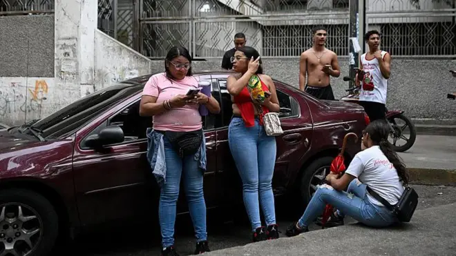 Un grupo de personas alrededor de un auto rojo en Caracas luego de un sismo.