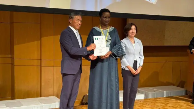 Foto of di acting acting ambassador of Nigeria to Japan, Mrs. Florence Akinyemi and Yoshikuni Watanabe, di mayor of Kisarazu, as im present di certificate from diJapanese government naming Kisarazu as di hometown of Nigerians.