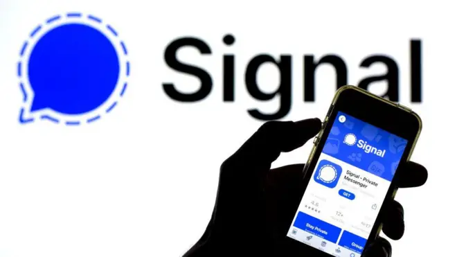 Una mano sujeta un móvil con la aplicación Signal en la pantalla