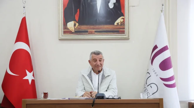 Güzelbahçe Belediye Başkanı Mustafa Günay bir masada, mikrofona konuşurken görülüyor