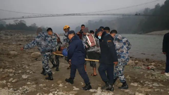 बस दुर्घटनामा परेका एक घाइते व्यक्तिलाई उद्धार गर्दै सुरक्षाकर्मीहरू 