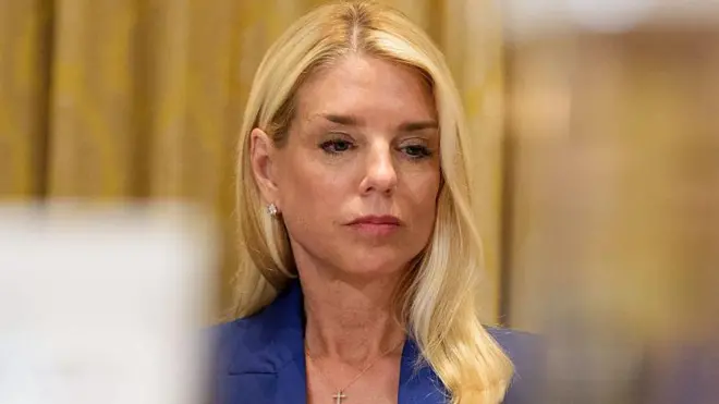 A procuradora-geral dos Estados Unidos, Pam Bondi, fotografada vestindo um terno azul e olhando para baixo durante uma audiência.