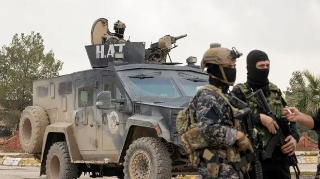 Güvenlik güçleri, 9 Şubat 2026'da Suriye'nin kuzeydoğusundaki Haseke kırsalında düzenlenen ortak ziyaret sırasında zırhlı bir aracın önünde duruyor