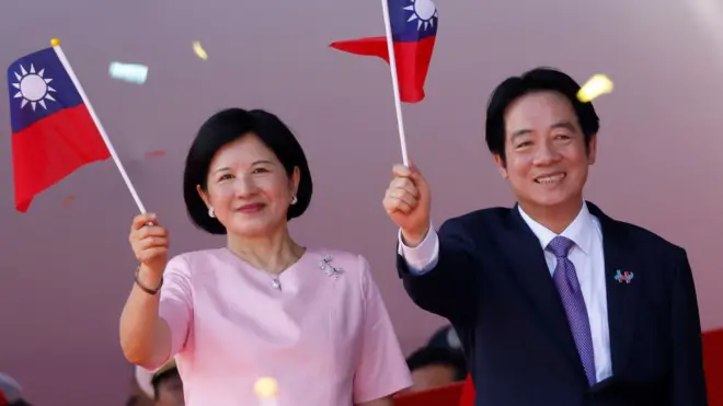 台北总统府前国庆大会上台湾总统赖清德（右）与夫人吴玫如（左）挥舞青天白日满地红小旗（10/10/2025）