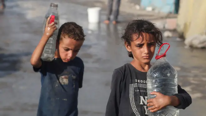طفلان في غزة يحملان أوعية فيها ماء