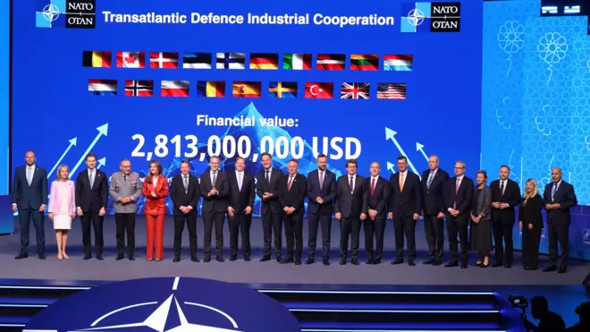 NATO liderleri sahnede poz veriyor. Arkada "Transatlantik Savunma Sanayi İş Birliği" yazıyor. Başlığın altında ülke bayrakları ve anlaşmaların 2,8 milyar dolar değerinde olduğu yazıyor.
