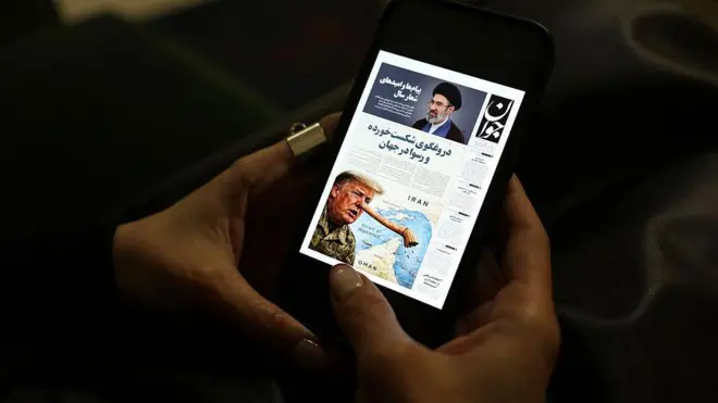 شاشة هاتف تحتوي صفحة من صحيفة إيرانية عليها صورتين واحدة للمرشد الإيراني الأعلى الجديد والأخرى للرئيس الأمريكي دونالد ترامب