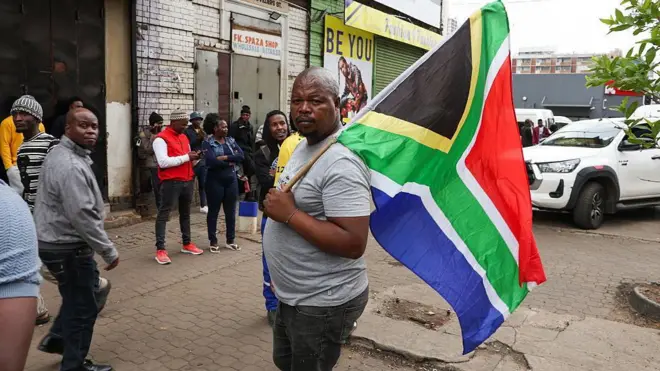 Man hold South Africa flag with some odas for di back