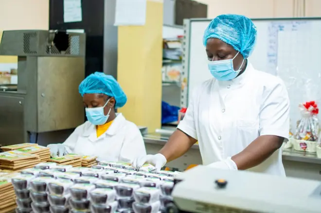 Deux femmes en tenue de travail devant des pots de chocolot