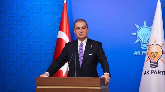 Ömer Çelik yanında AKP bayrağı olan kürsüde açıklama yaparken 