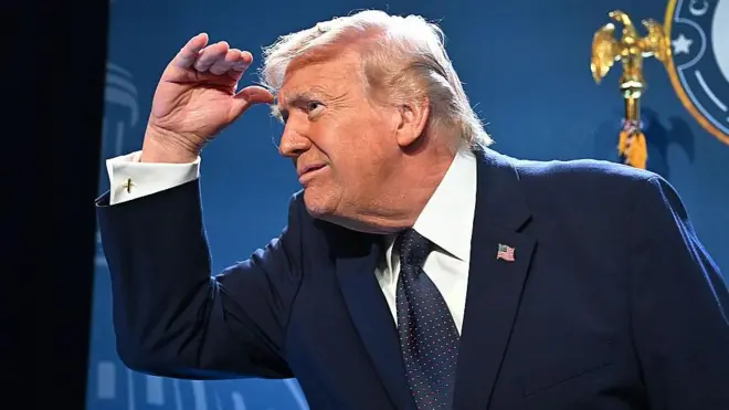 دونالد ترامپ در مراسمی دستش را بالای چشم‌هایش سایه‌بان کرده