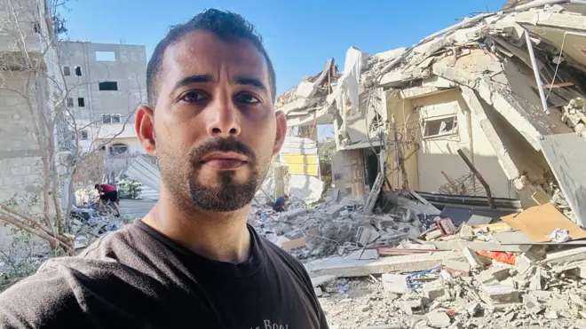 الشاعر الفلسطيني مصعب أبو توهة أمام منزله المهدم في قطاع غزة 