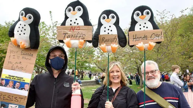 المتظاهرون يحملون لافتات تظهر طيور البطريق