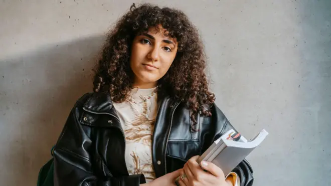 طالبة جامعية تمسك دفاتر وكتب