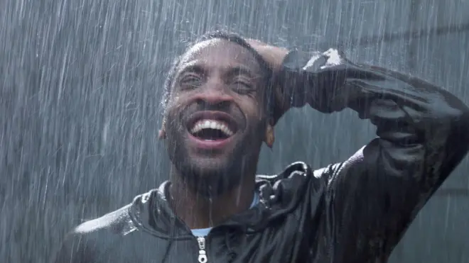 Young man dey stand inside rain, as e dey look up