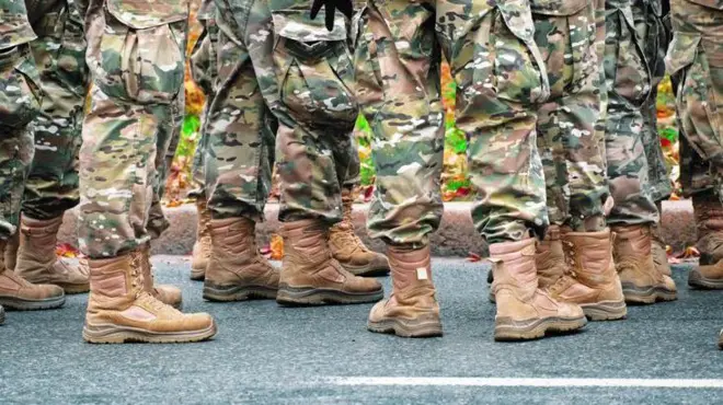 گروهی از سربازان با لباس‌های استتار و چکمه‌های تاکتیکی که در جاده آسفالت ایستاده‌اند - عکس آرشیوی