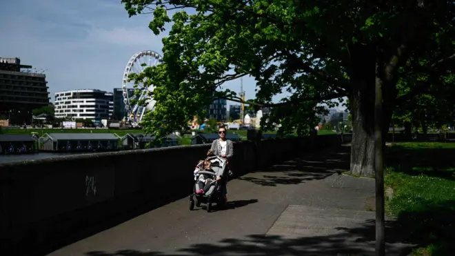 Kobieta z dzieckiem spaceruje między kwitnącymi drzewami