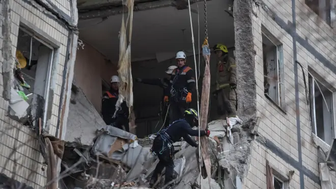 Несколько спасателей работают в разрушенной квартире в многоэтажном доме.