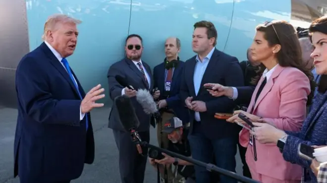 Trump, Air Force One uçağı yanında mikrofonlar önünde basına konuşuyor.