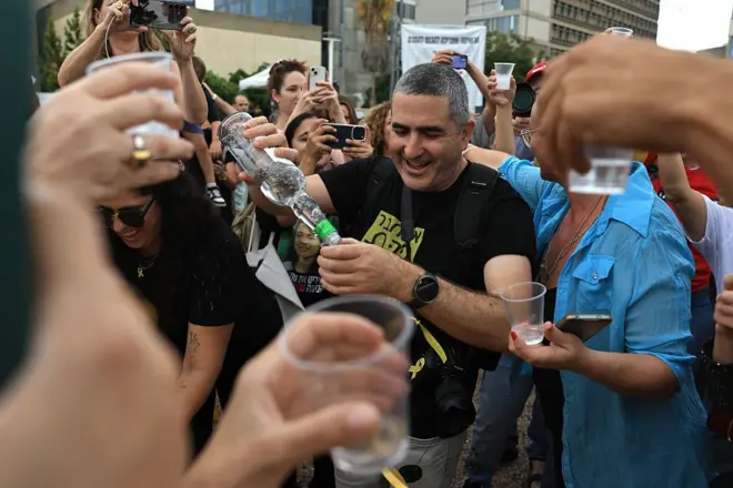 Pessoas com copos e colocando bebidas em comemoração