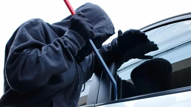 Ladrón intentando abrir la puerta de un auto.