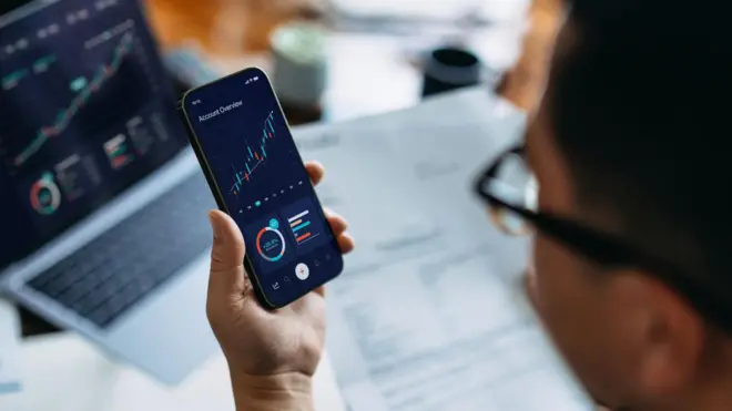 Un hombre viendo la cotización de una criptomoneda en su teléfono.
