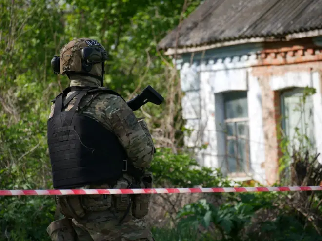 Поліцейський в екіпіруванні стоїть перед будинком