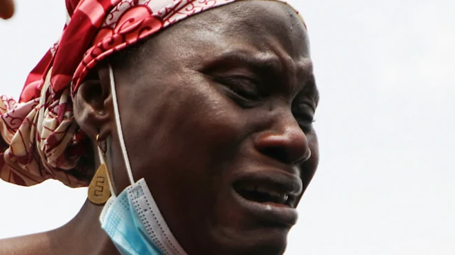 Une femme qui pleure, un masque facial attaché à sa mâchoire.