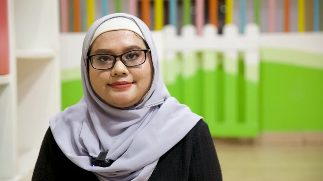 Nur Yanayirah, mengenakan hijab berwarna ungu muda dan atasan warna hitam. Dia melihat ke kamera, mengenakan kacamata dengan frame hitam.