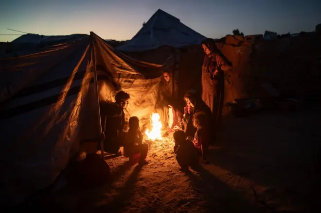 صابرين، فلسطينية نازحة، 42 عاماً، وهي أم لسبعة أطفال، تطبخ على نار مفتوحة جنوب قطاع غزة، 30 نوفمبر/تشرين الثاني 2025، حيث تواجه ظروفاً إنسانية قاسية في مخيم غير رسمي في خان يونس، تفاقمت بسبب الفقر المدقع والطقس القاسي. 