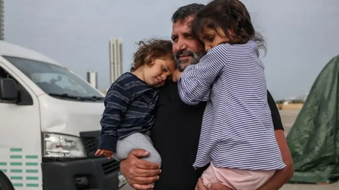 liban, muškarac nosi dve devojčice