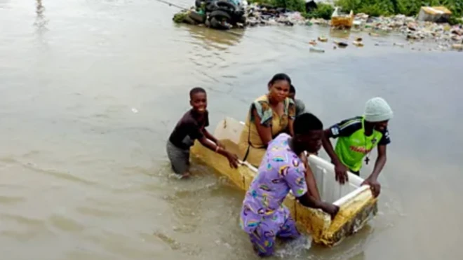 Awọn ọdọkunrin n fi firiiji to ti bajẹ gbe arabinrin kan kọja lori omi latari ẹkun omi to waye nipinlẹ Ogun sẹyin